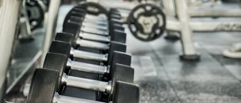A gym with weightlifting equipment and a person working out in the background.