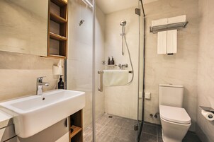 Ein modernes Badezimmer mit einer Duschkabine aus Glas, einem weißen Waschbecken und einer Toilette.