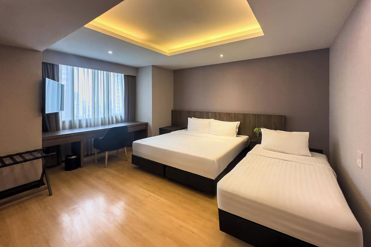 Habitación de hotel con dos camas, un escritorio, una silla y un televisor.