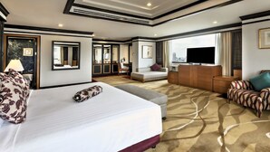 Habitación de hotel con una cama grande, un sofá, un televisor y un escritorio.