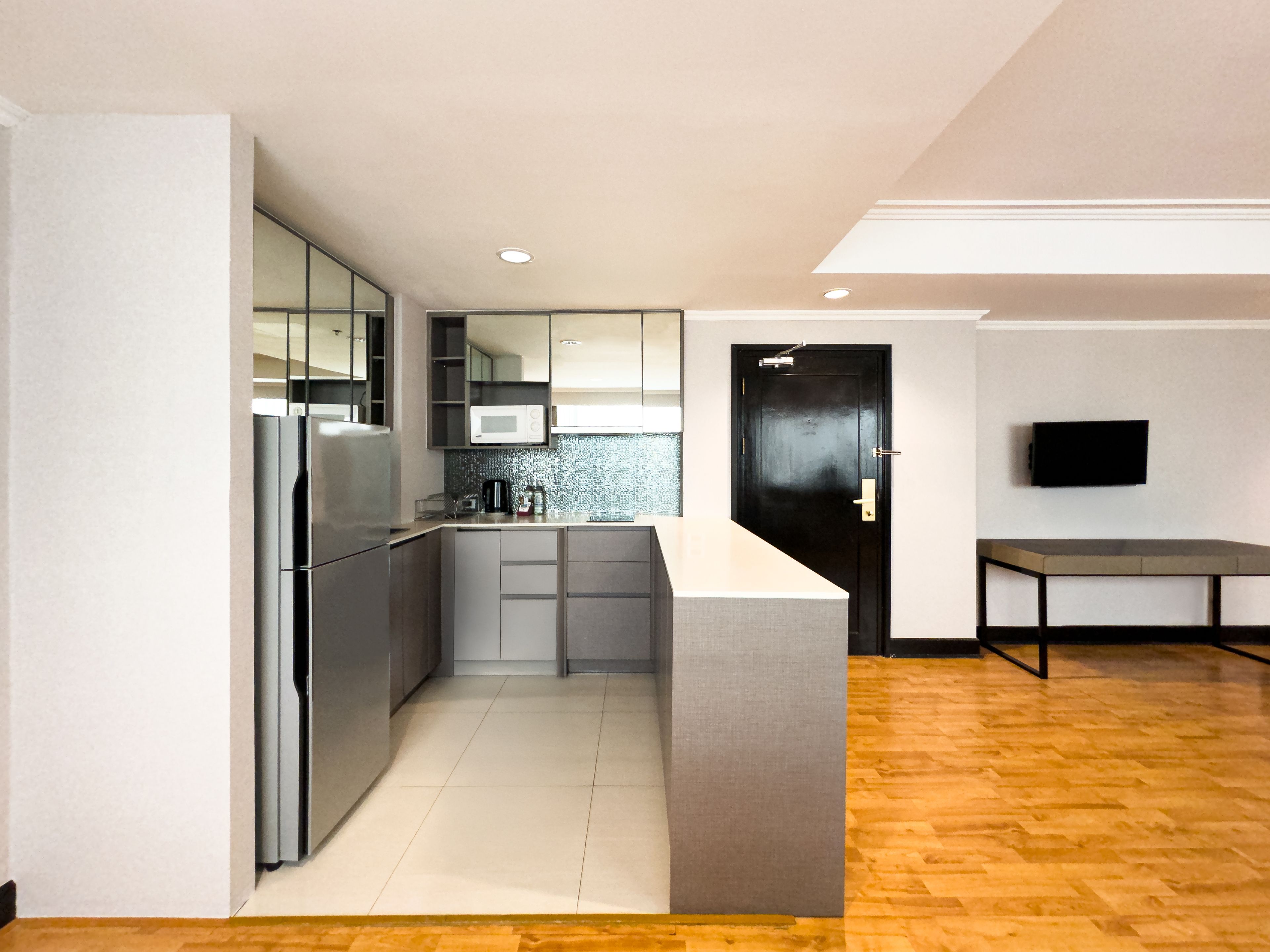 Una cocina moderna con refrigerador integrado, microondas y una puerta de madera oscura.