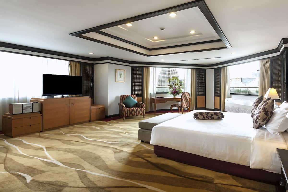 Habitación de hotel con una cama grande, un escritorio, un televisor y vistas a la ciudad.