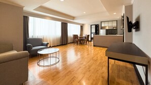 Una habitación de hotel moderna con sala de estar, una mesa de comedor y una cocina.