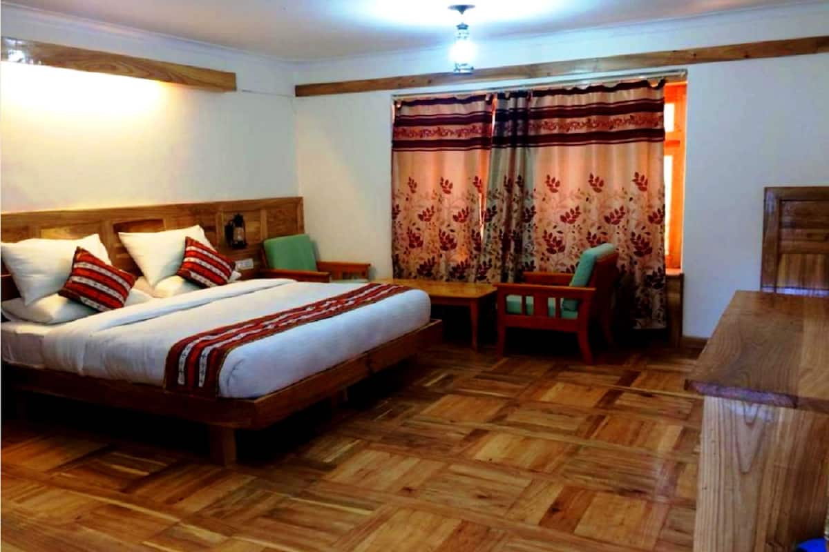 A bedroom with a wooden bed, a wooden desk, and a chair.