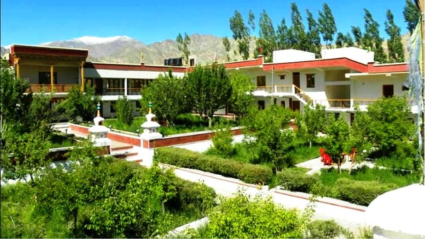 A traditional building with multiple balconies, surrounded by lush greenery and a clear blue sky. - TIH Global Family Resort - Saboo - Leh (Leh)