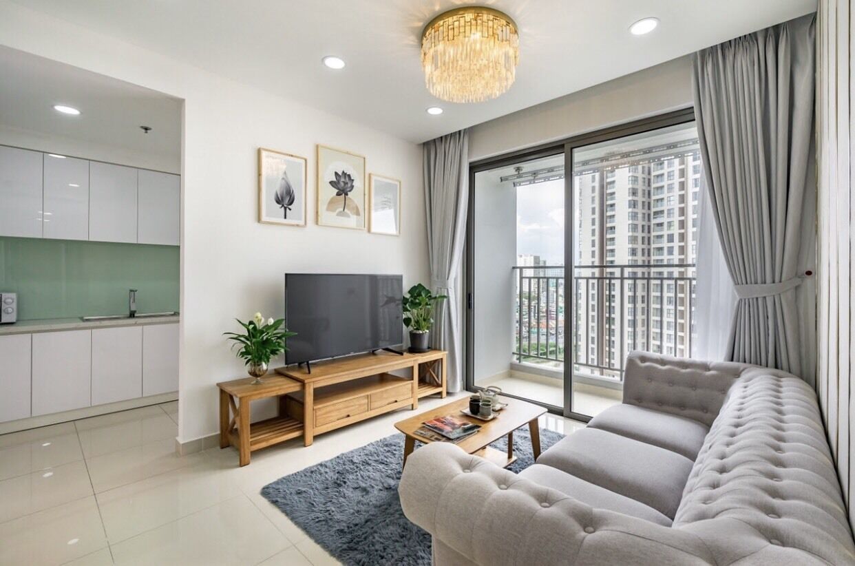 Una sala de estar moderna con un sofá, televisor y un balcón con vista a la ciudad.
