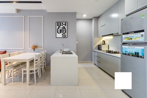 A modern kitchen with a central island, white cabinetry, and a Panasonic refrigerator.