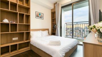 Camera d'albergo con un letto grande, scaffali in legno, vista sulla città e un balcone con tende.