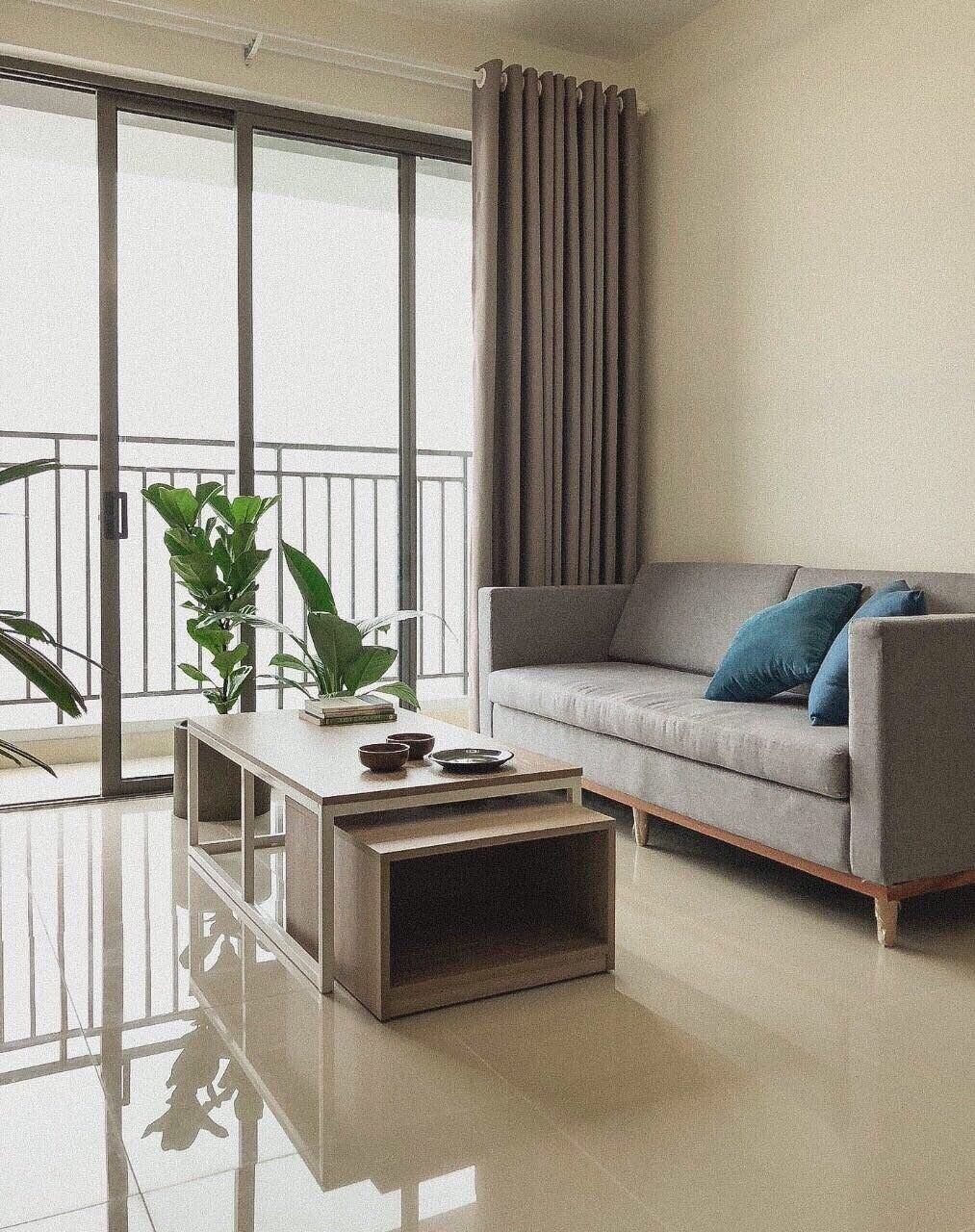 Una sala de estar moderna con un sofá gris, una mesa de centro y un ventanal con cortinas.