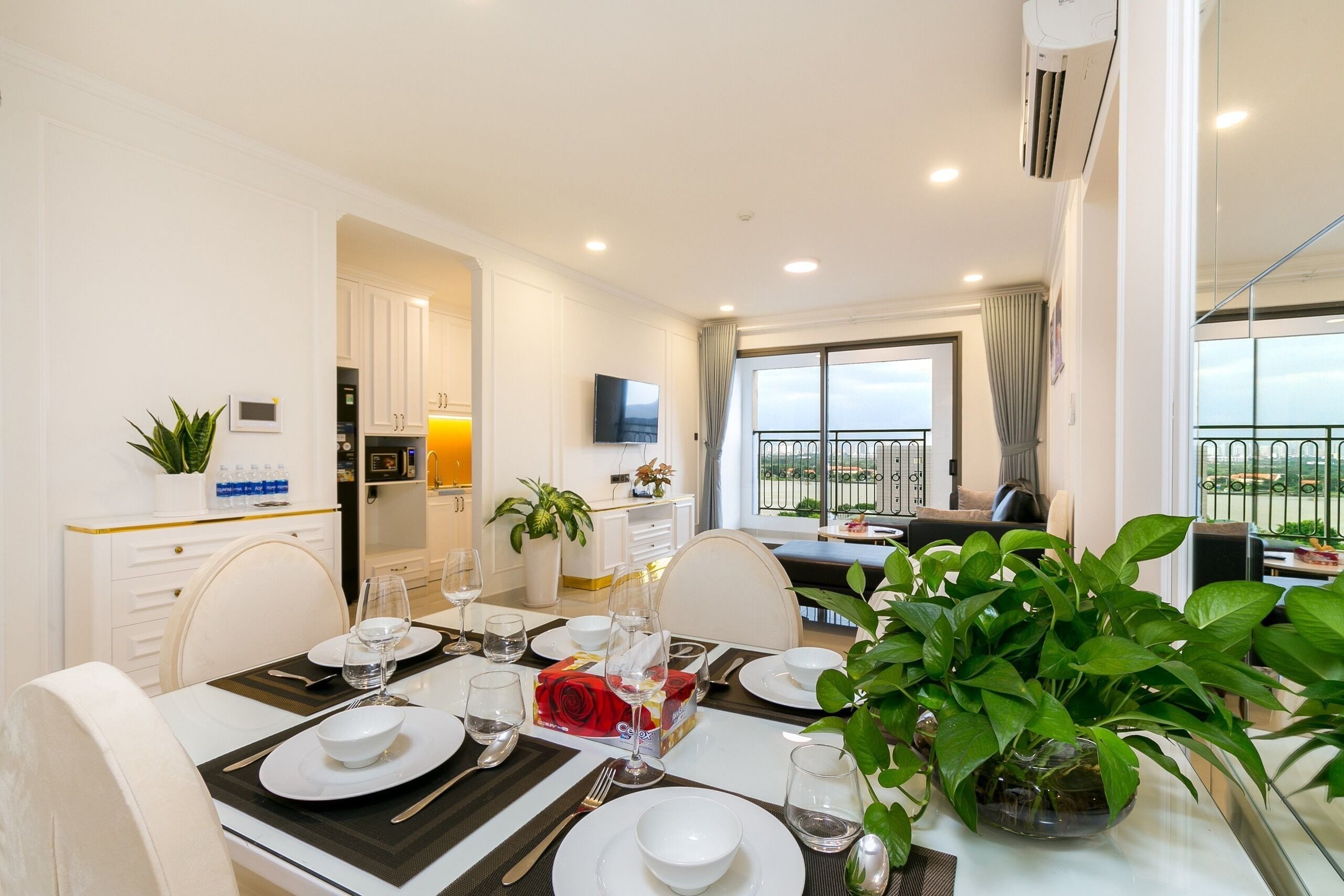 Een goed verlichte eethoek met een tafel voor vier personen, een keuken op de achtergrond en een balkon met uitzicht.