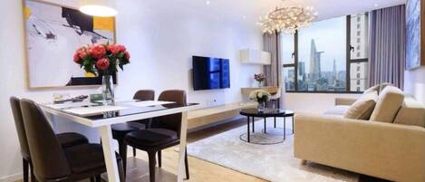 En moderne stue med spiseplads, en sofa, en lysekrone og udsigt over byen.