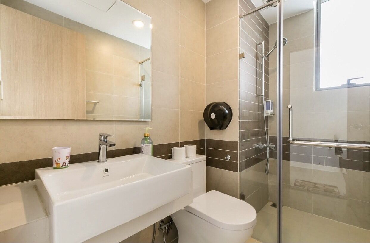 A bathroom with a white sink, toilet, and a glass-enclosed shower area.
