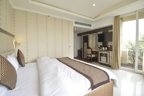 A hotel room with a large bed, a desk, and a view of the outdoors. - The Royal Castle (Dharamshala)