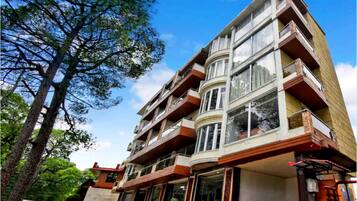 Un edificio de varios pisos con balcones, ventanas amplias y un cielo despejado.