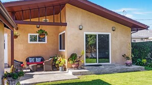A house with a covered patio, a sliding glass door, and a well-maintained lawn. - Spacious private house (Lawndale)