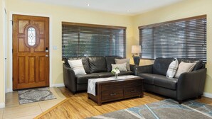 A living room with two leather sofas, a wooden coffee table, and a door with a stained glass window. - Spacious private house (Lawndale)