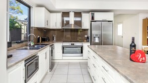 Een moderne keuken met witte kasten, roestvrijstalen apparatuur, een ingebouwde oven en een groot raam.