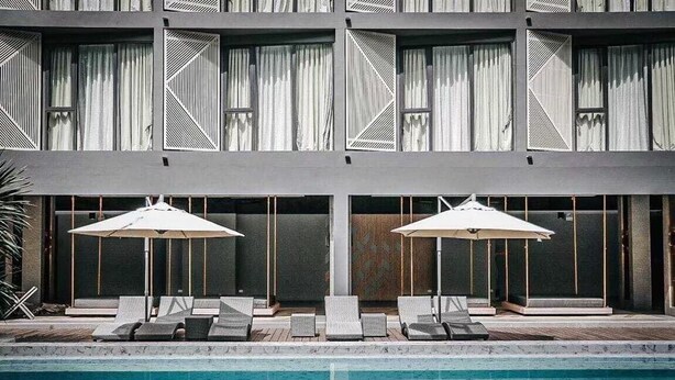 A modern building with a swimming pool, lounge chairs, and umbrellas. - Canalis Suvarnabhumi Airport Hotel – Free Scheduled shuttle from Hotel to Suvarnabhumi Airport (Bangkok)