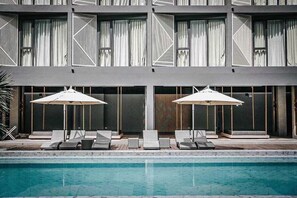 Ein modernes Gebäude mit Pool, Liegestühlen und Sonnenschirmen.