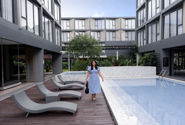 Una piscina al aire libre, sillones reclinables de piscina