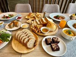 Een eettafel met diverse gerechten, waaronder brood, wafels en een soepkom.