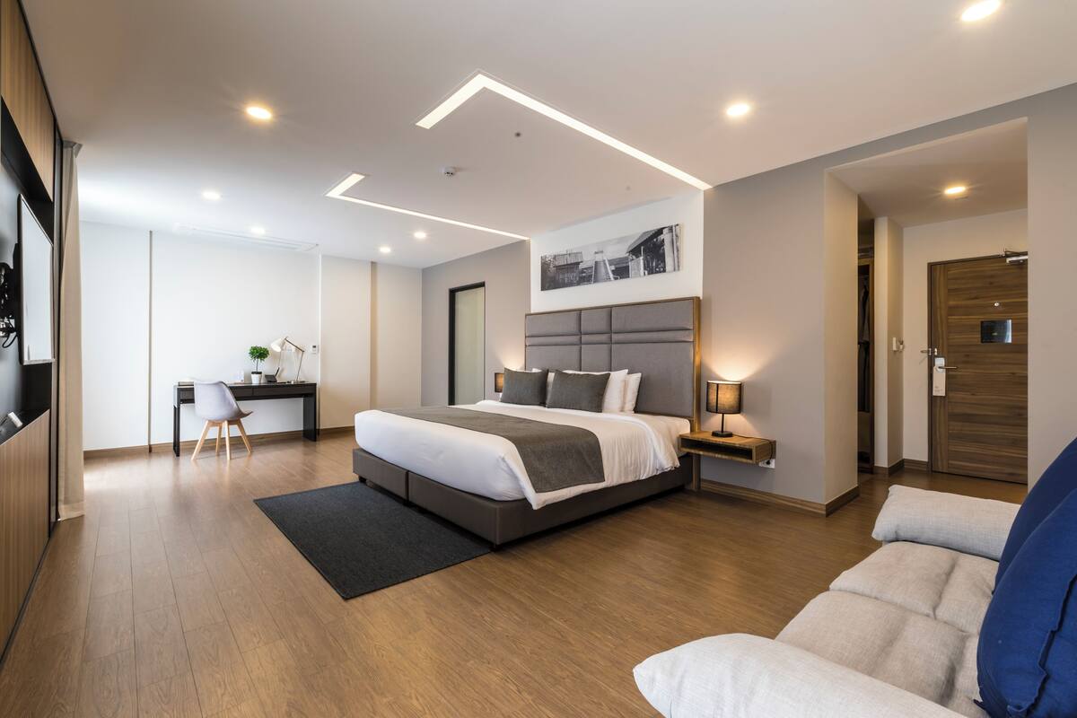 Une chambre à coucher moderne avec un grand lit, des tables de chevet, un bureau et une chaise.