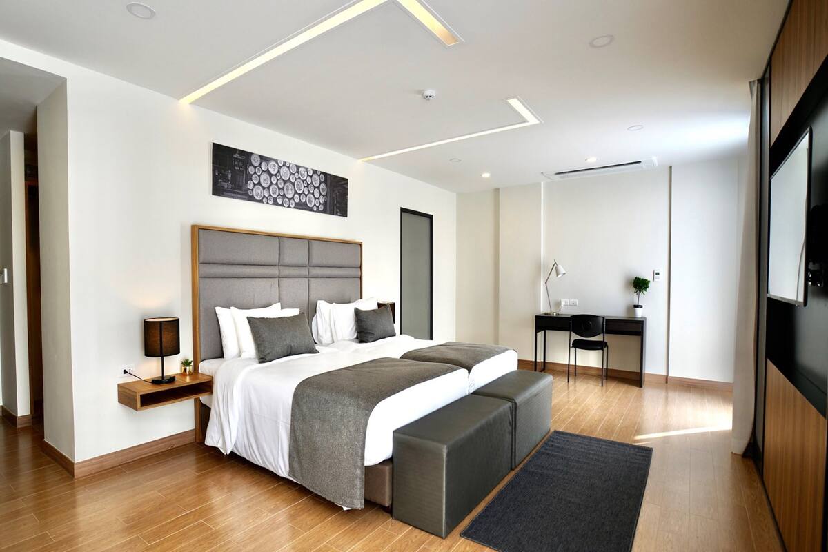 Une chambre à coucher moderne avec un grand lit, des tables de chevet, un bureau et une chaise.