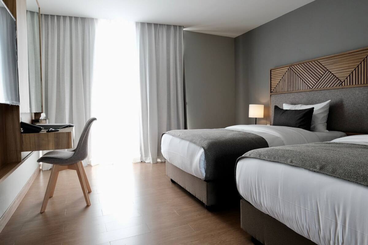 Une chambre d’hôtel avec deux lits, un bureau avec une chaise et un téléviseur.