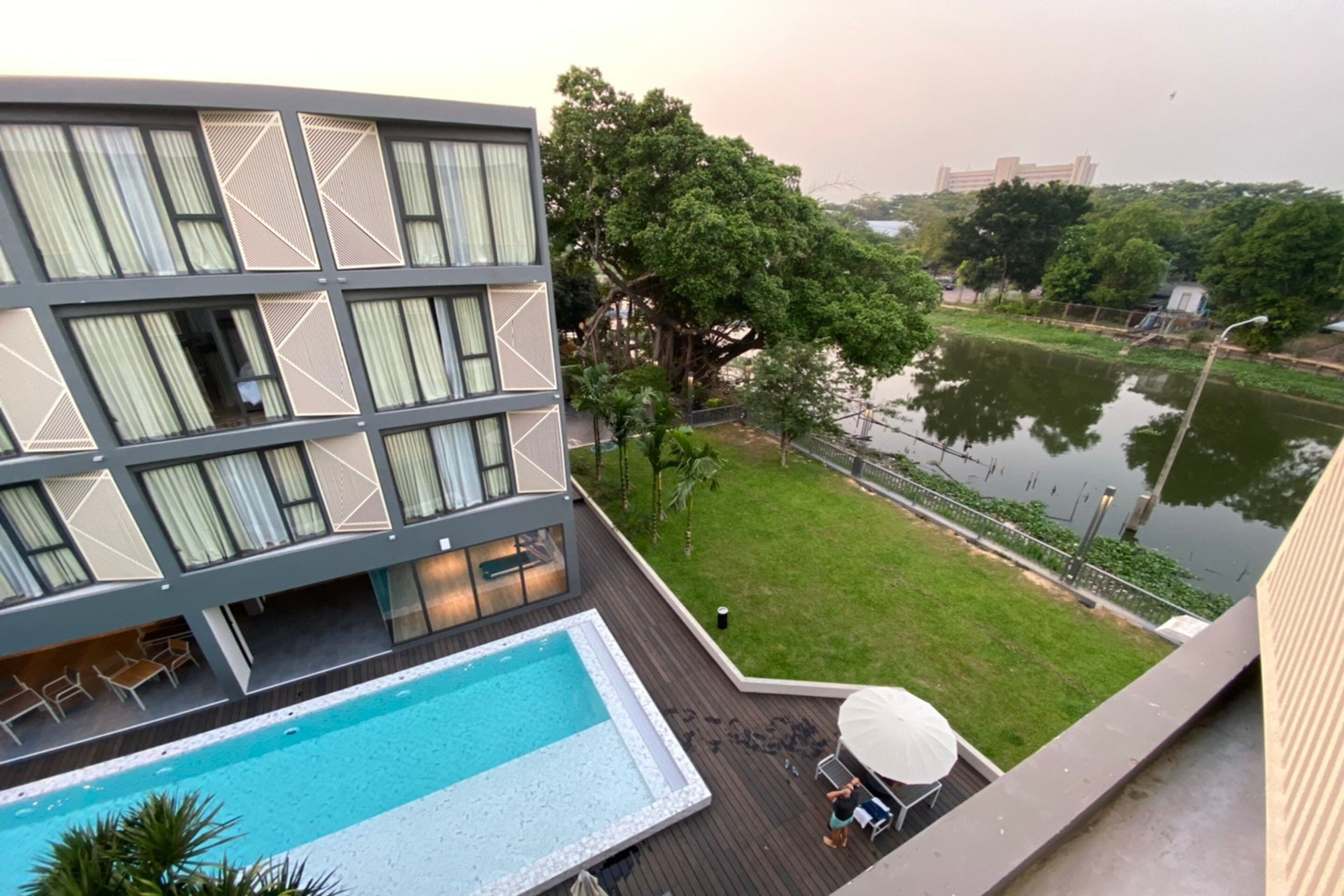 Un hotel moderno con piscina, mobiliario exterior y vistas a un lago.
