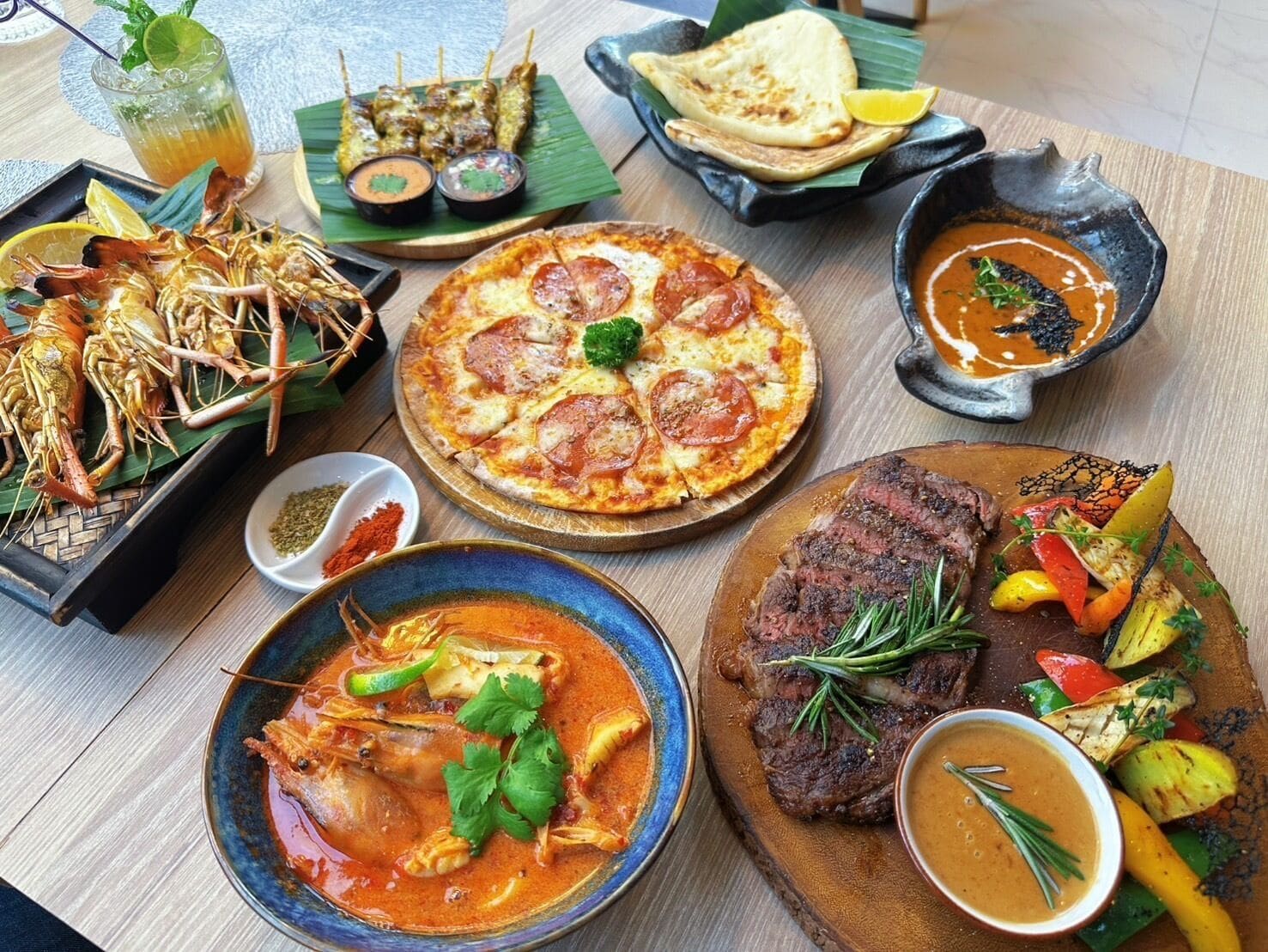Diversa varietat de plats, incloent marisc, pizza, entrecot i un bol de sopa, que indica una àmplia oferta gastronòmica.
