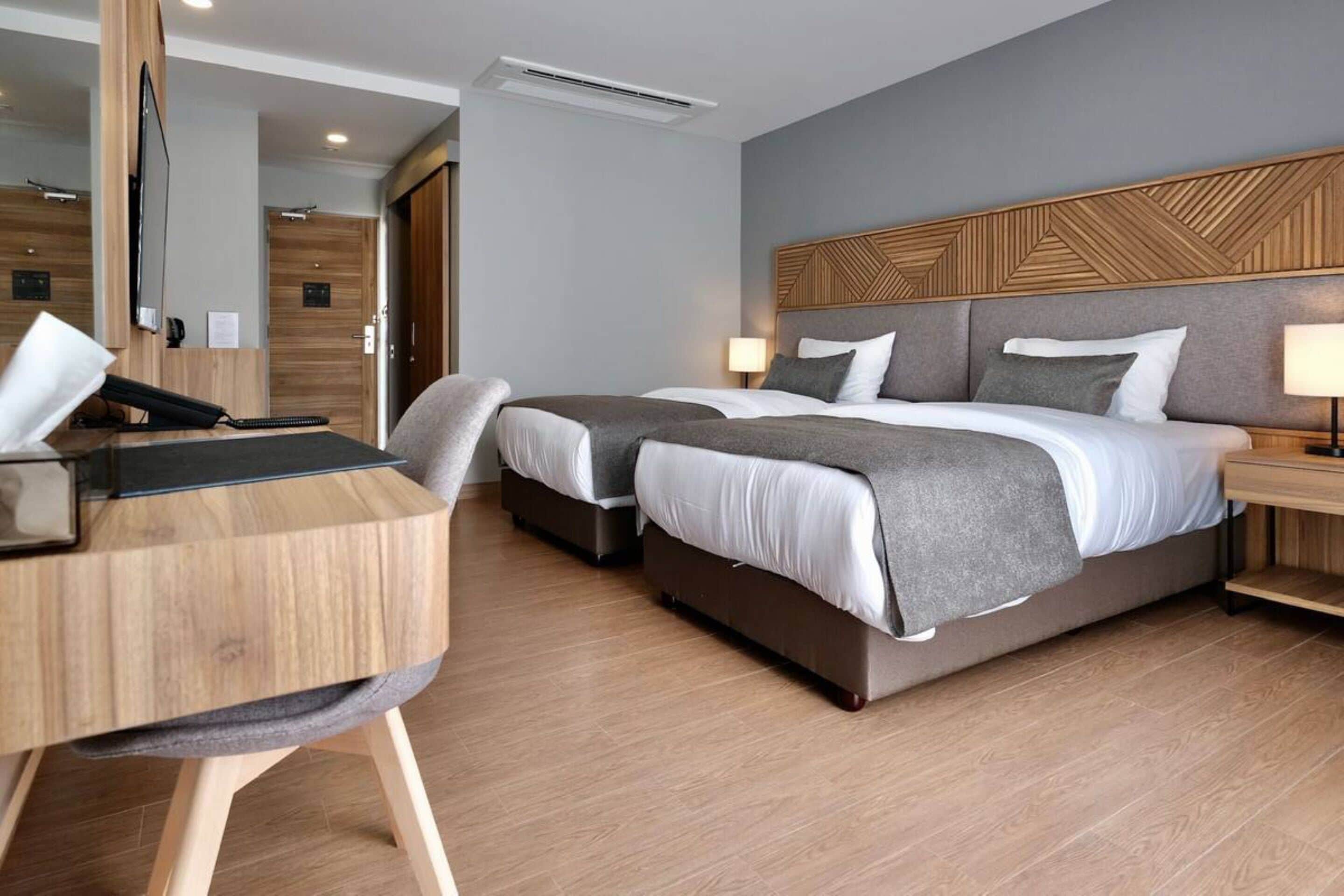 A hotel room with a large bed, a desk, and a chair.