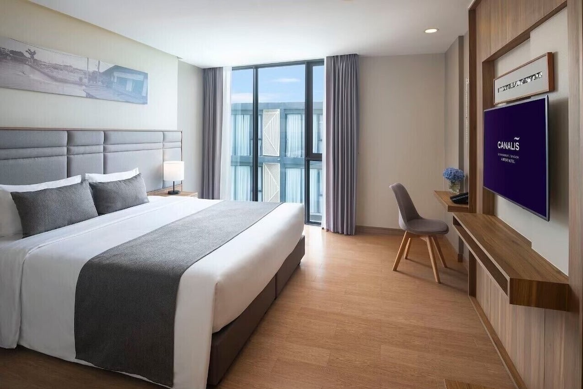 Une chambre d’hôtel avec un grand lit, une télévision, un bureau et une vue sur l’extérieur.