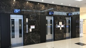 A modern elevator area with marble walls, multiple elevators, and digital displays. - Toyoko Inn Matsumoto-eki Higashi-guchi (Matsumoto)