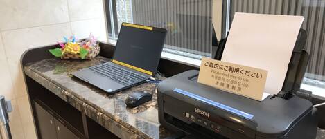 A counter with a laptop, a printer, and a sign in a foreign language.