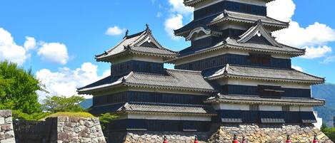 A traditional Japanese castle with multiple tiers and a red bridge in front.