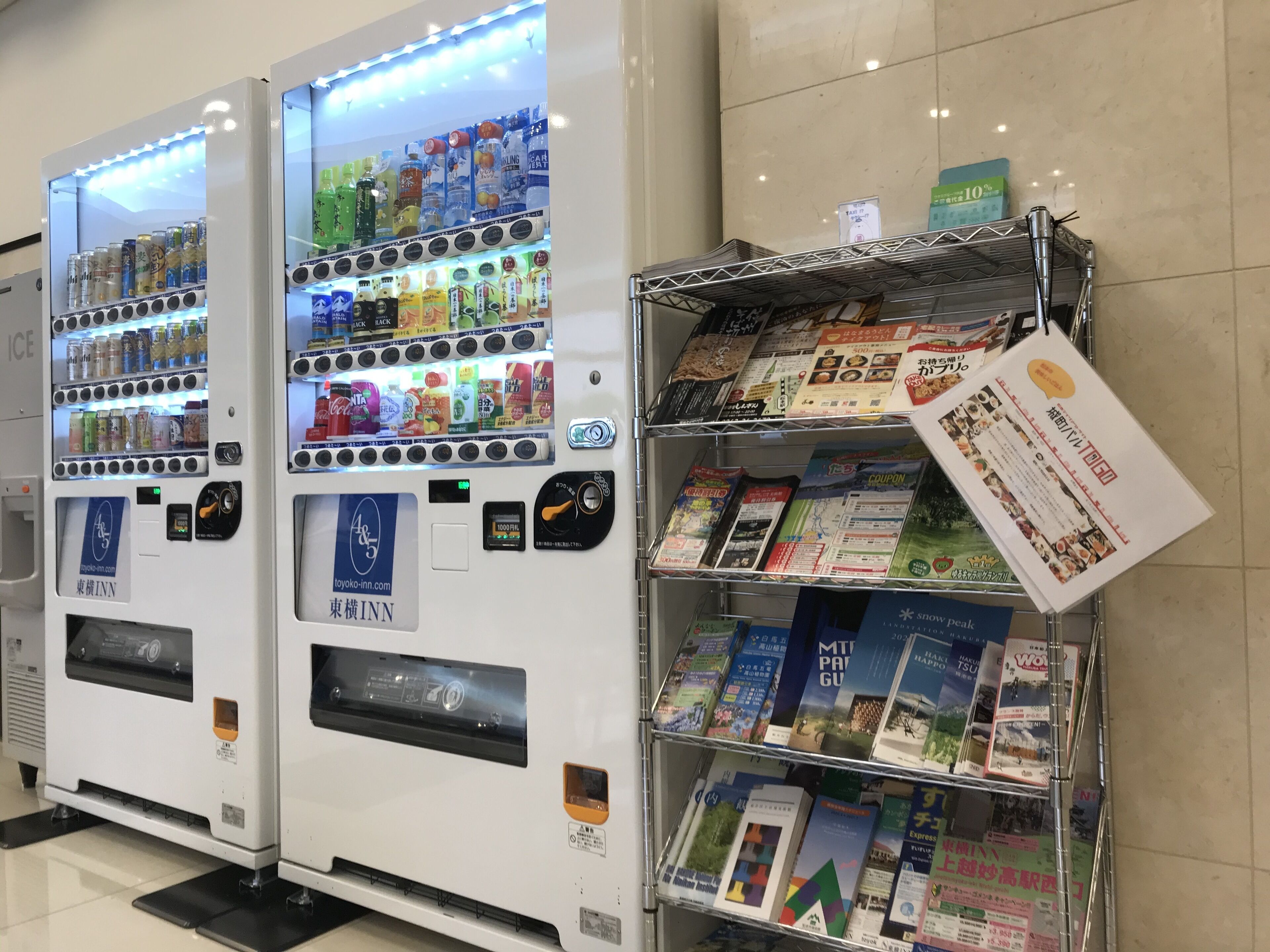 Two vending machines stocked with beverages and snacks, and a rack of travel brochures.