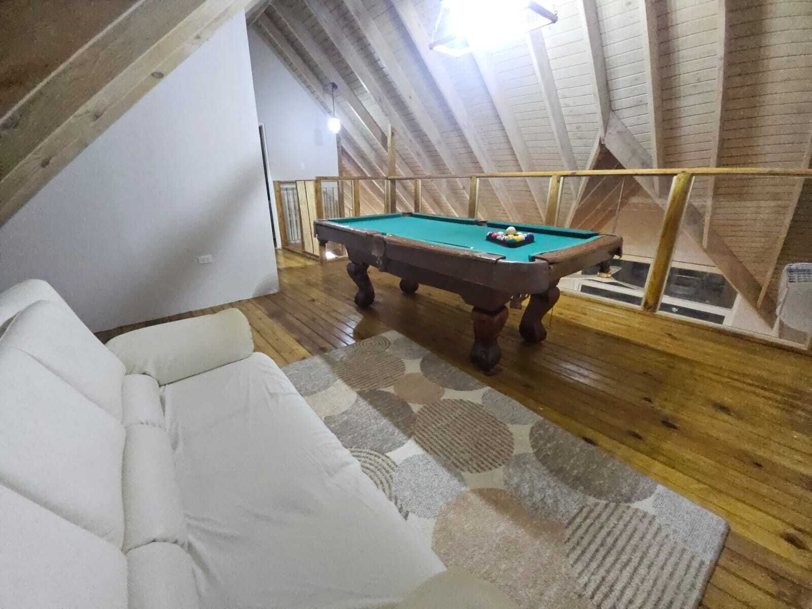 Une pièce avec une table de billard, un canapé blanc et un plancher en bois.
