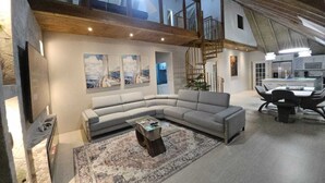 A spacious living area with a large L-shaped sofa, a coffee table, and a staircase leading to an upper level. - Seacastles Apartments (Montego Bay)