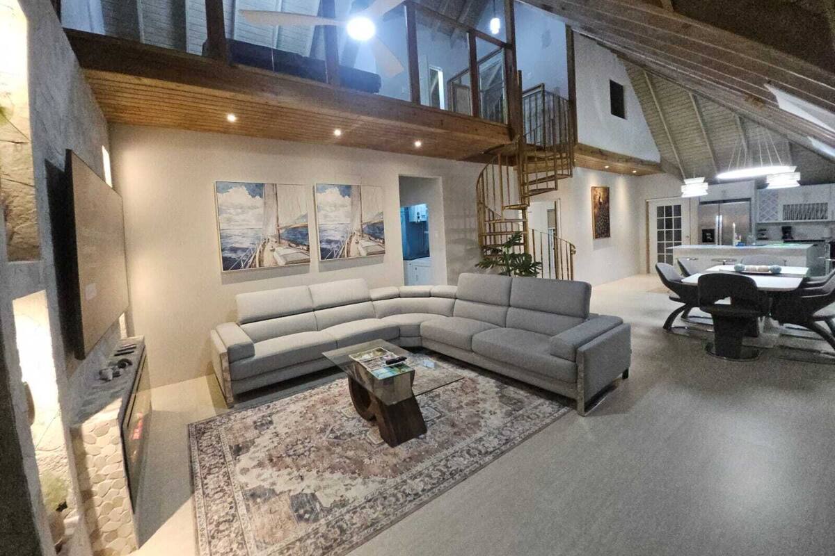 A spacious living area with a large L-shaped sofa, a coffee table, and a staircase leading to an upper level.