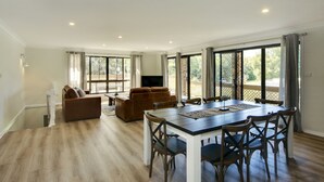 Un salón amplio con una mesa de comedor, sofás y ventanas grandes.