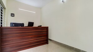 A reception desk with a wooden finish, a printer, and a laptop. - Itsy Hotels Rain Tulsi Stayz, Palarivattom Junction (Kanayannur)