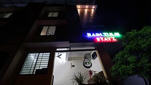 A building with a neon sign reading "RAIN TULSA STAYZ" and a reception area with a sign that says "RECEPTION". - Itsy Hotels Rain Tulsi Stayz, Palarivattom Junction (Kanayannur)