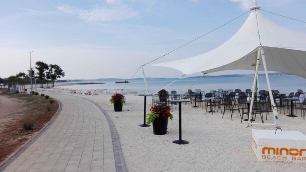 Eine Strandbar mit Außenbestuhlung und Meerblick.