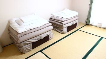 Dos camas con ropa de cama doblada en una habitación con suelo de tatami.