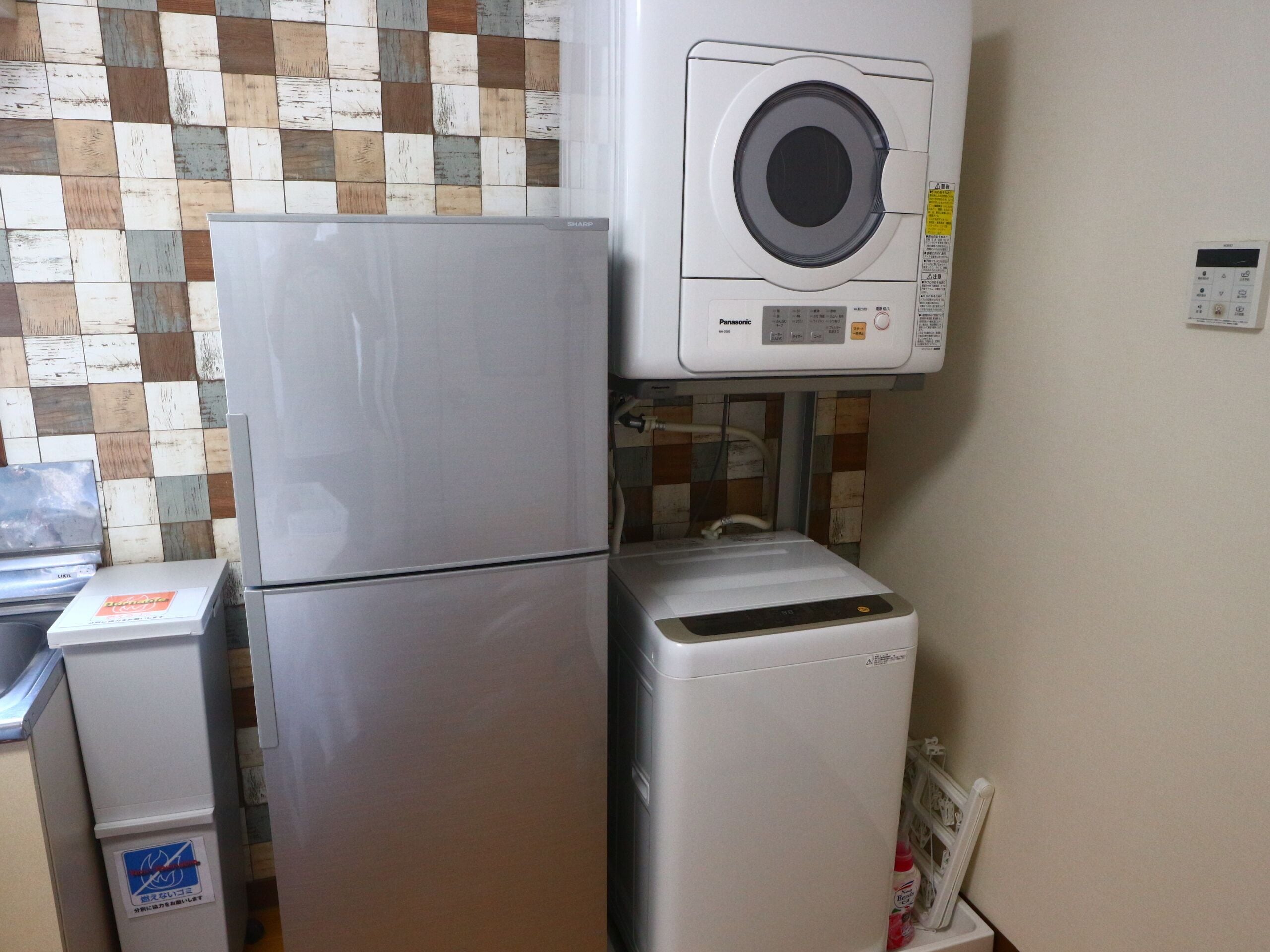 A compact kitchen with a refrigerator, a washing machine, and a microwave.