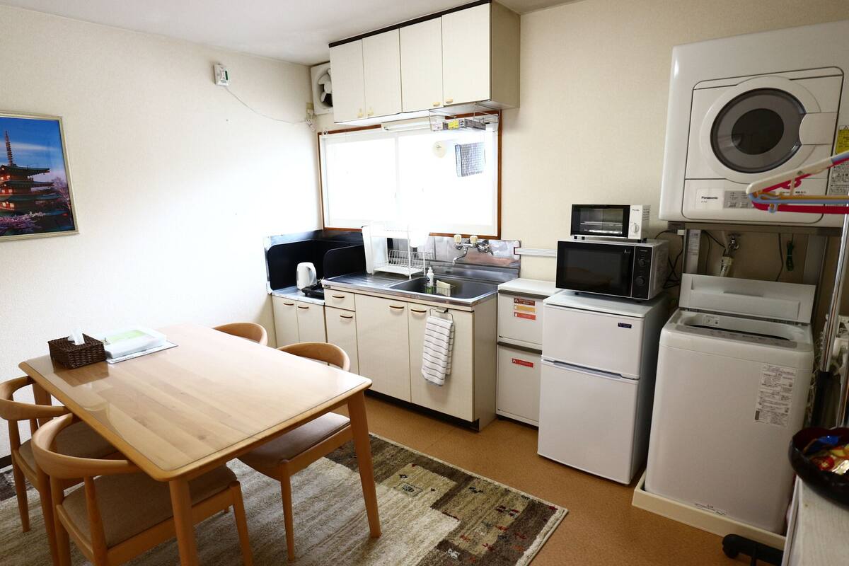 Cocina compacta con comedor, que incluye una mesa y sillas de madera, un lavabo, un microondas y un refrigerador.