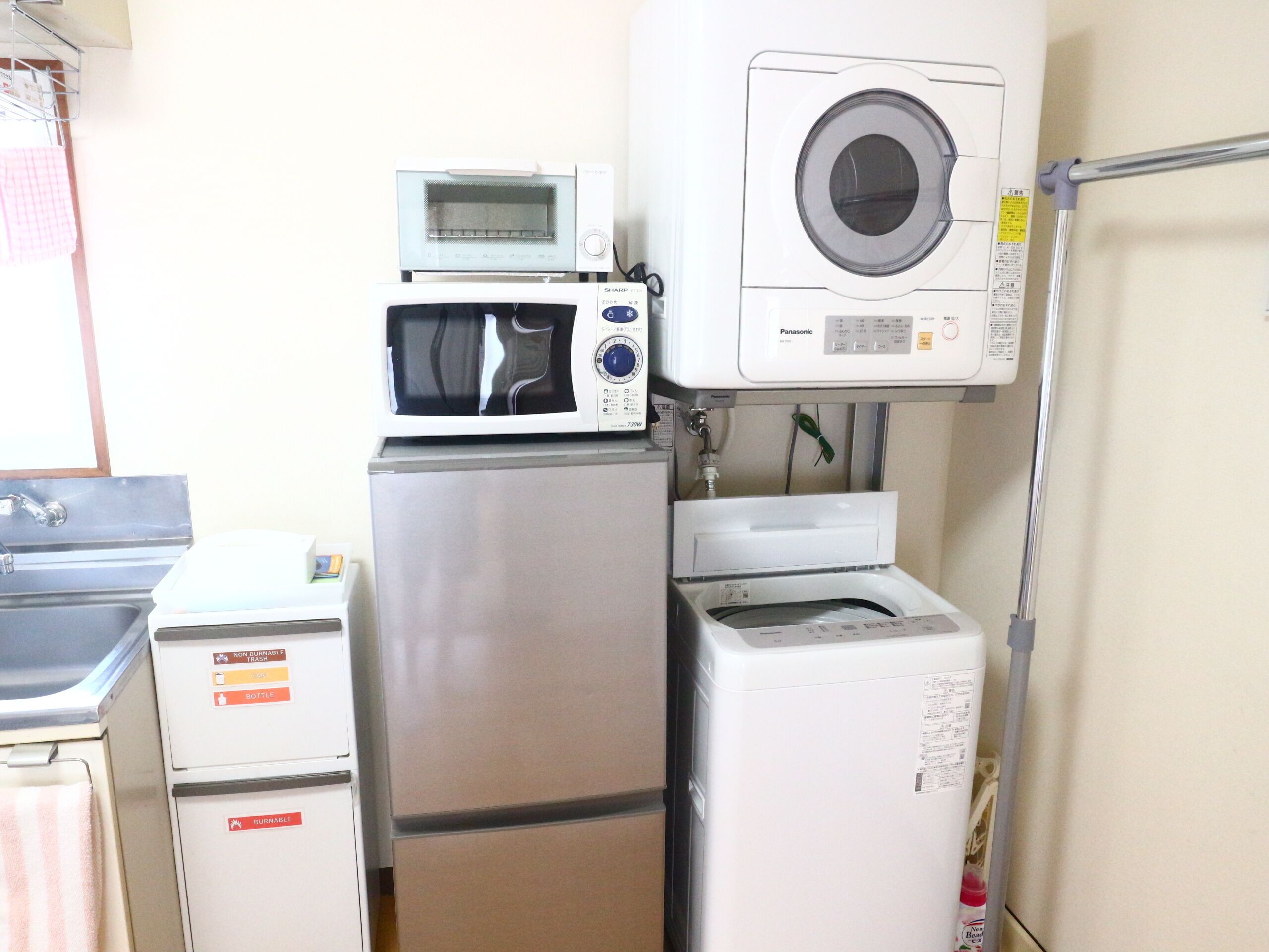 A compact kitchen with a microwave, a small oven, and a washing machine.
