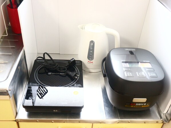 A kitchen with a black induction cooktop, a white electric kettle, and a black rice cooker. - Fujisan YOU Apartment (Fujiyoshida)