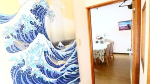 A room with a traditional Japanese wave-patterned curtain, a wooden door, and a view into a dining area with a table and chairs. - Fujisan YOU Apartment (Fujiyoshida)