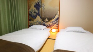 A hotel room with two beds, a traditional Japanese sliding door, and a wall with a wave painting. - Fujisan YOU Apartment (Fujiyoshida)
